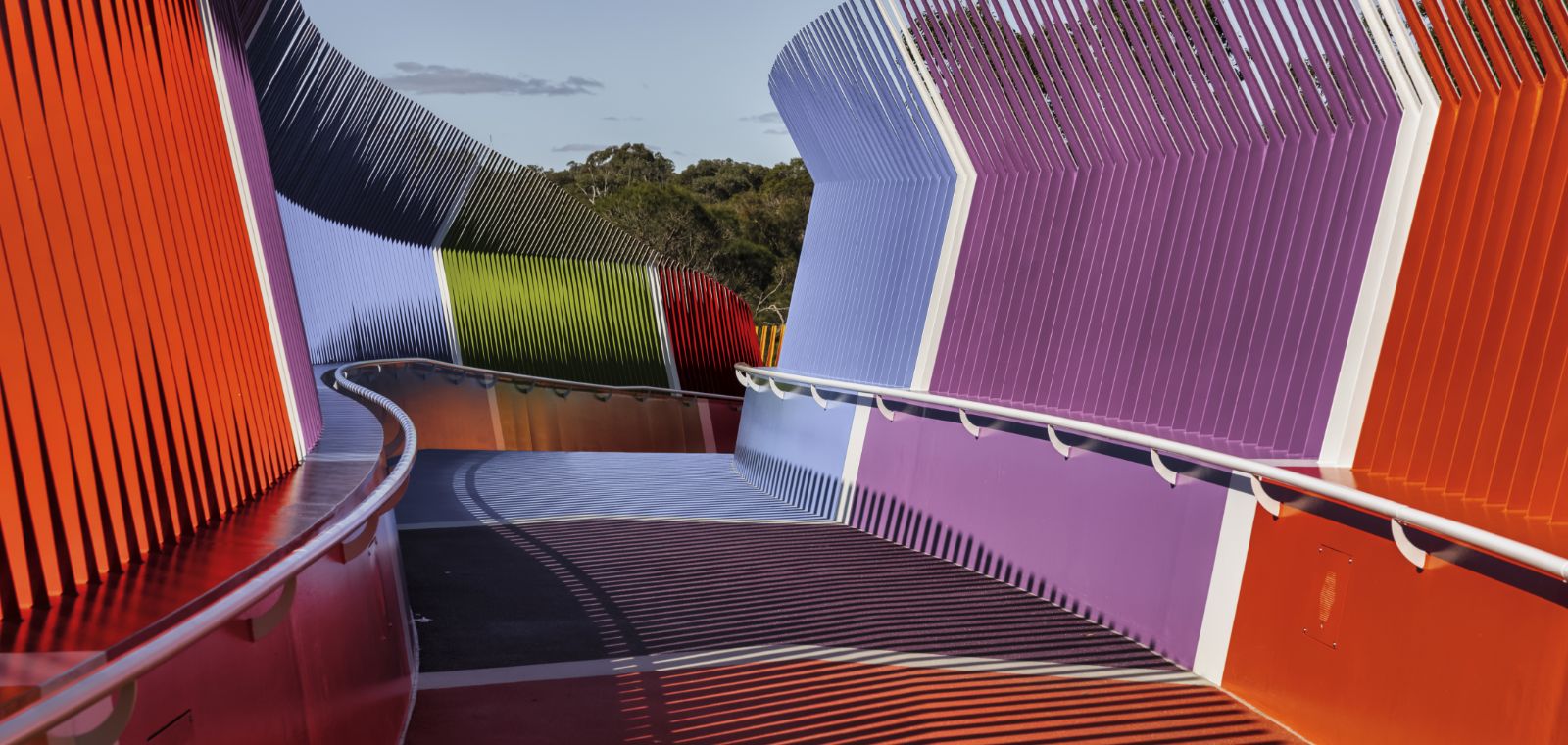 A wavy bridge with multicolored side walls offers pedestrians a clear path forward despite the apparent instability. 